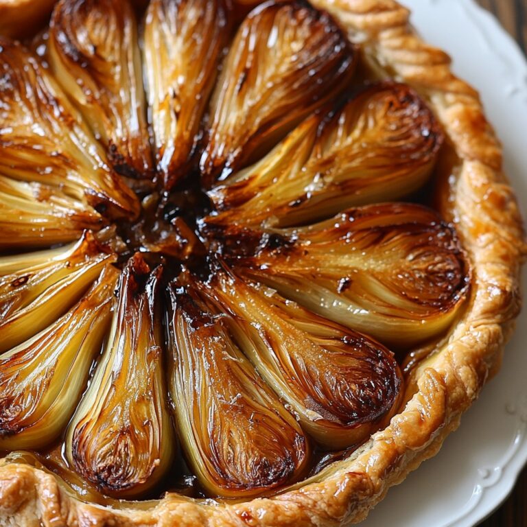Tarte renversée aux endives caramélisées façon tatin salée, dorée et brillante dans un plat de service