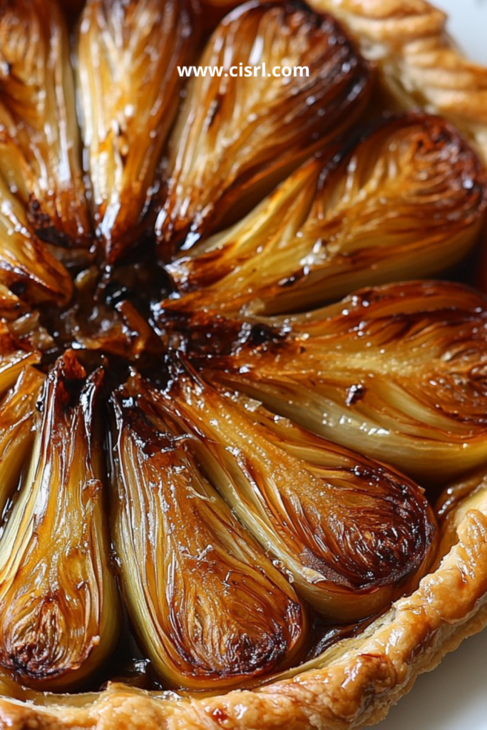 Tarte renversée aux endives caramélisées façon tatin salée, dorée et brillante dans un plat de service